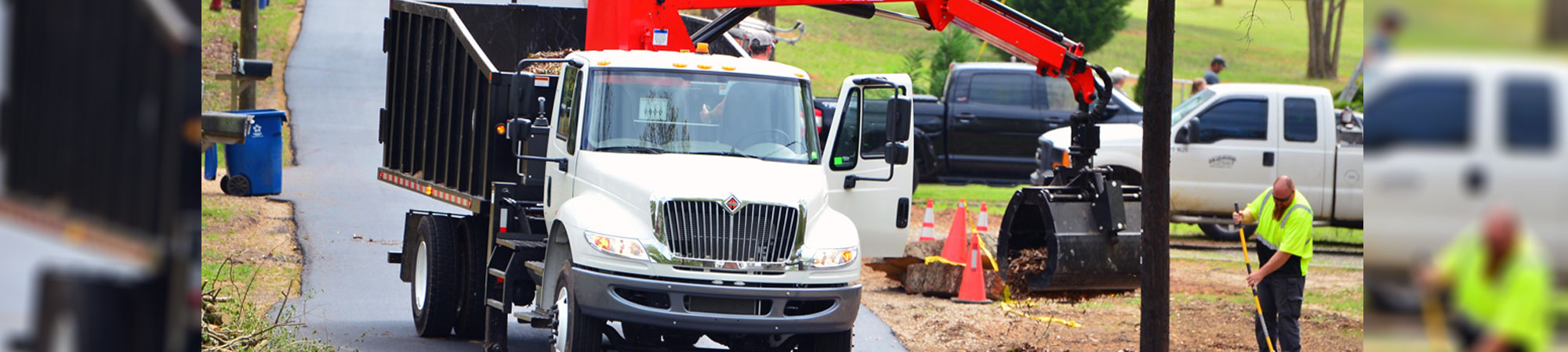 self-loading dump truck picking up leaves on side of road